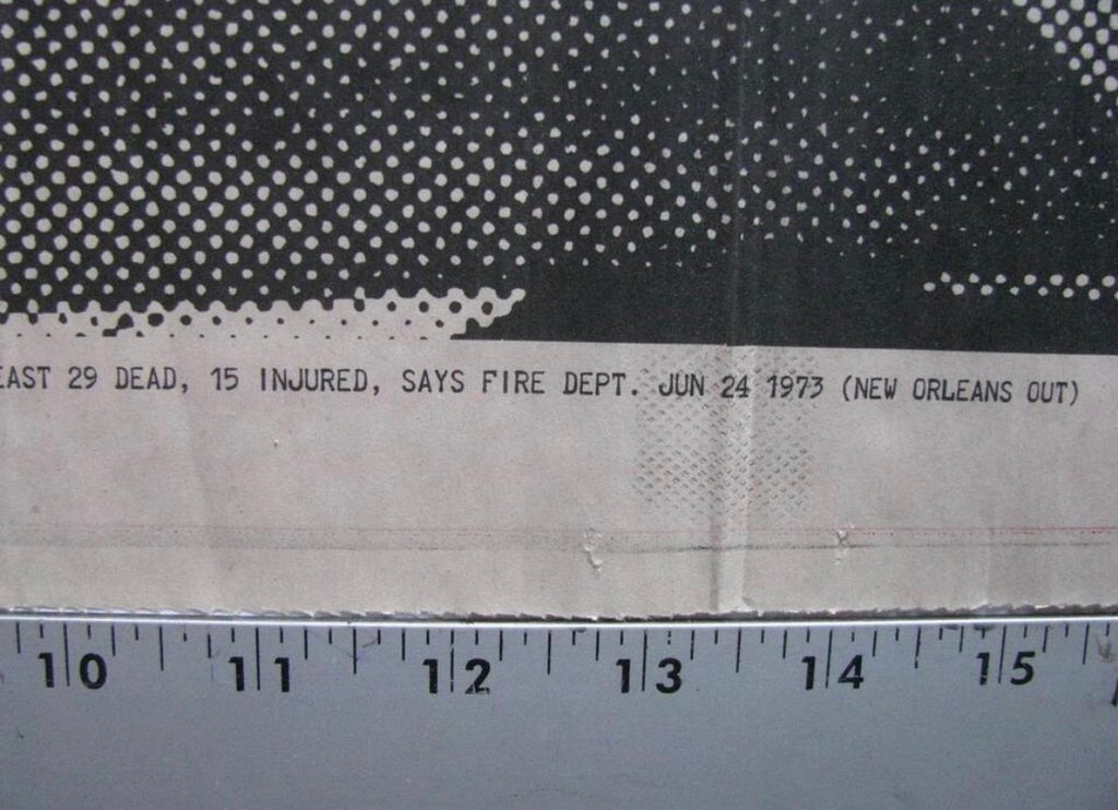 A close-up of a printed fabric or paper sample with a black-and-white halftone pattern at the top, a white printed text band across the middle, and a ruler along the bottom to show scale.