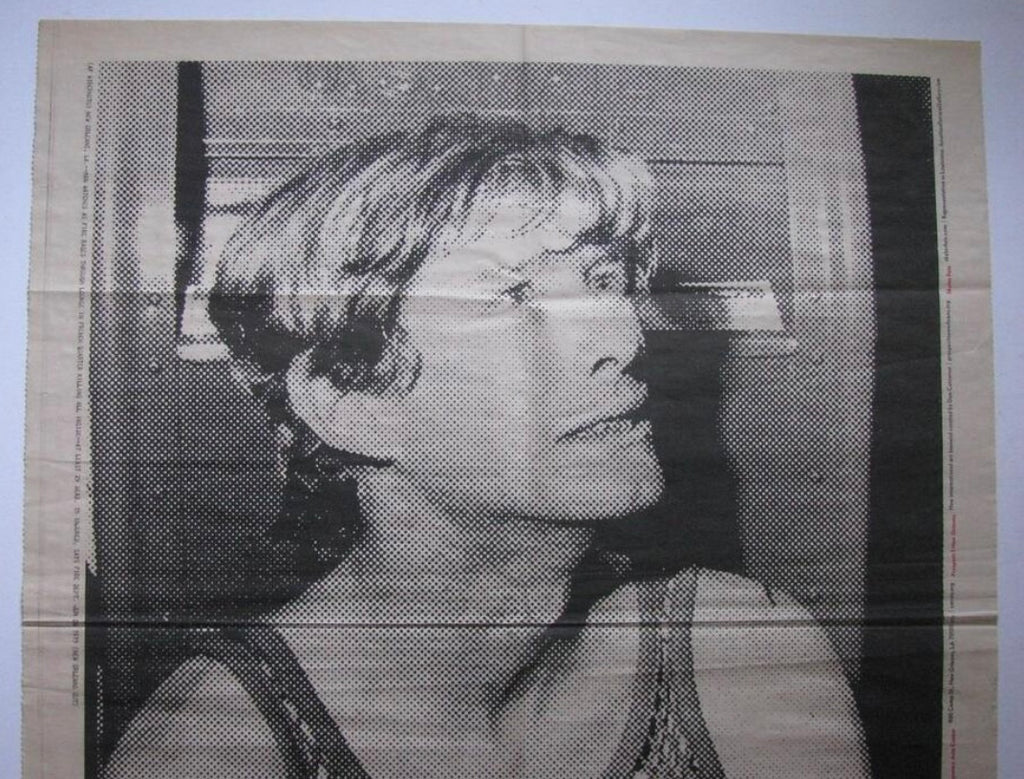 A black and white halftone portrait print of a survivor looking upward, shown against a light beige background with visible fold lines.