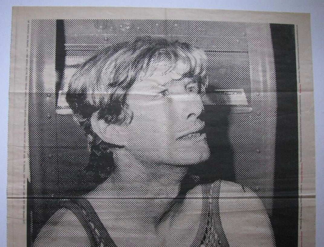 A black and white halftone portrait print of a survivor looking upward, shown against a light beige background with visible fold lines.