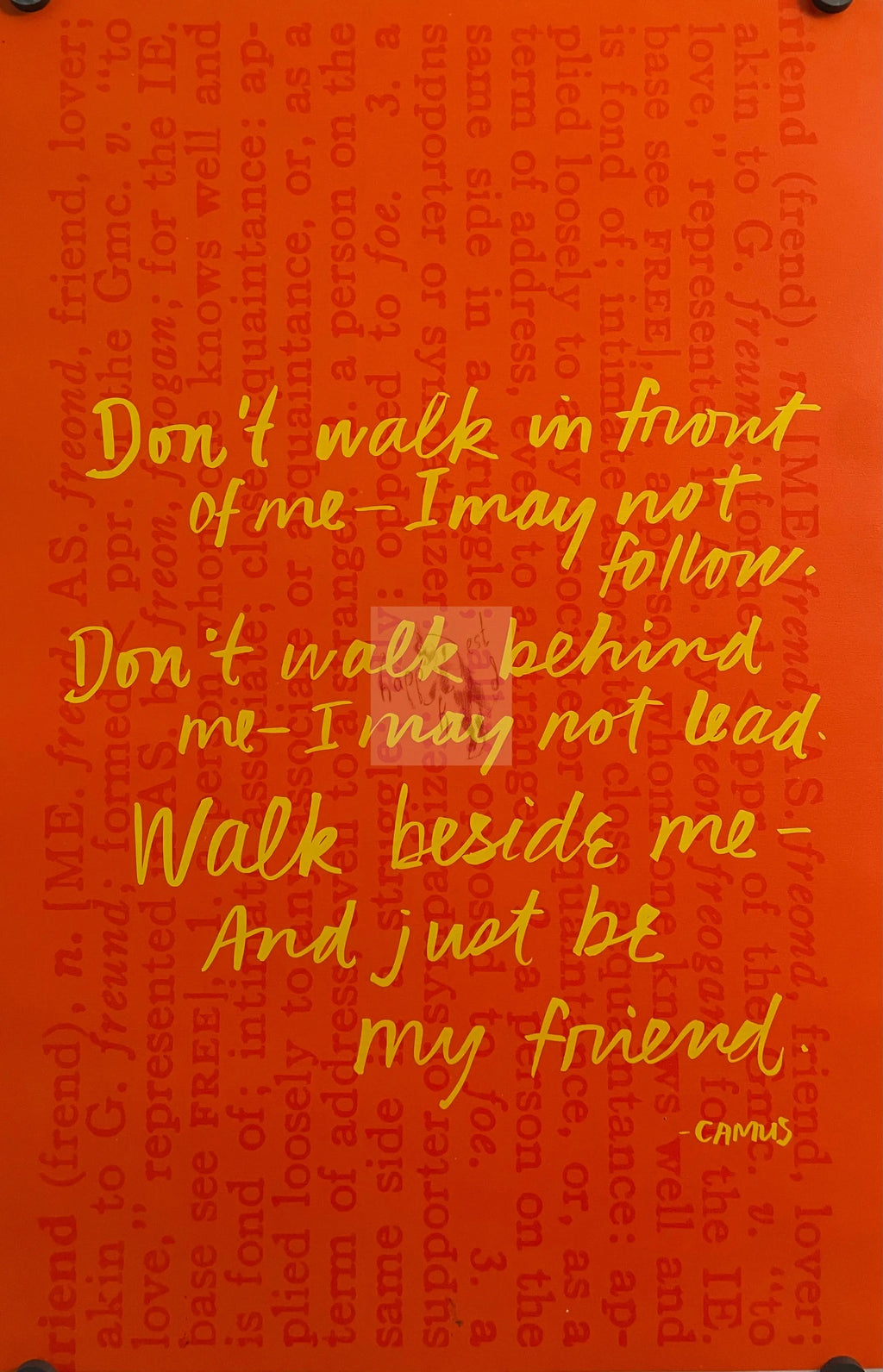 A motivational poster featuring text in yellow on an orange background, with a quote about walking in front of someone and being their friend.