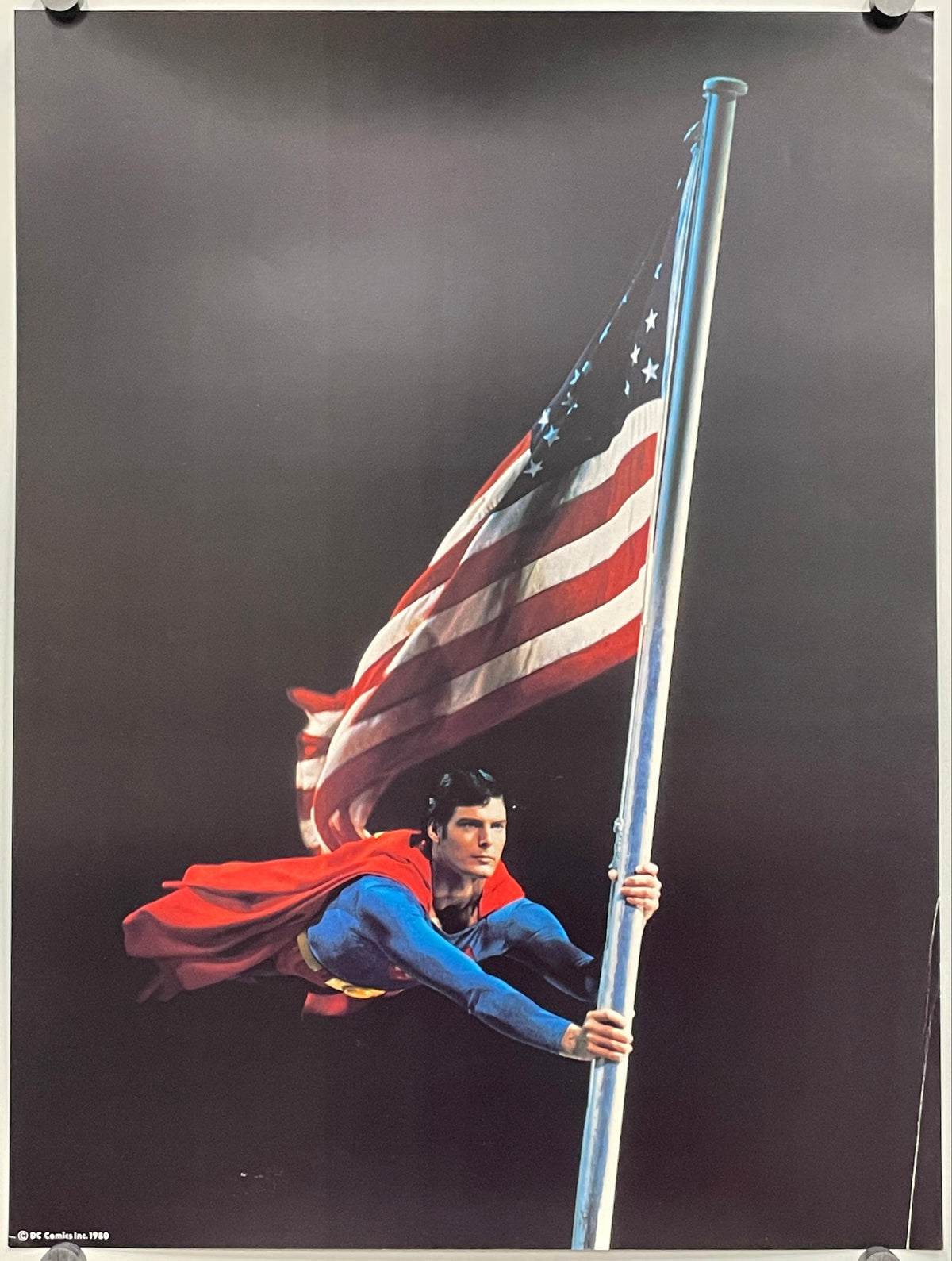 Superman holding an American flag against a dark background