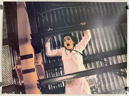 Person in a pink coat inside a cage-like structure with a dramatic expression.