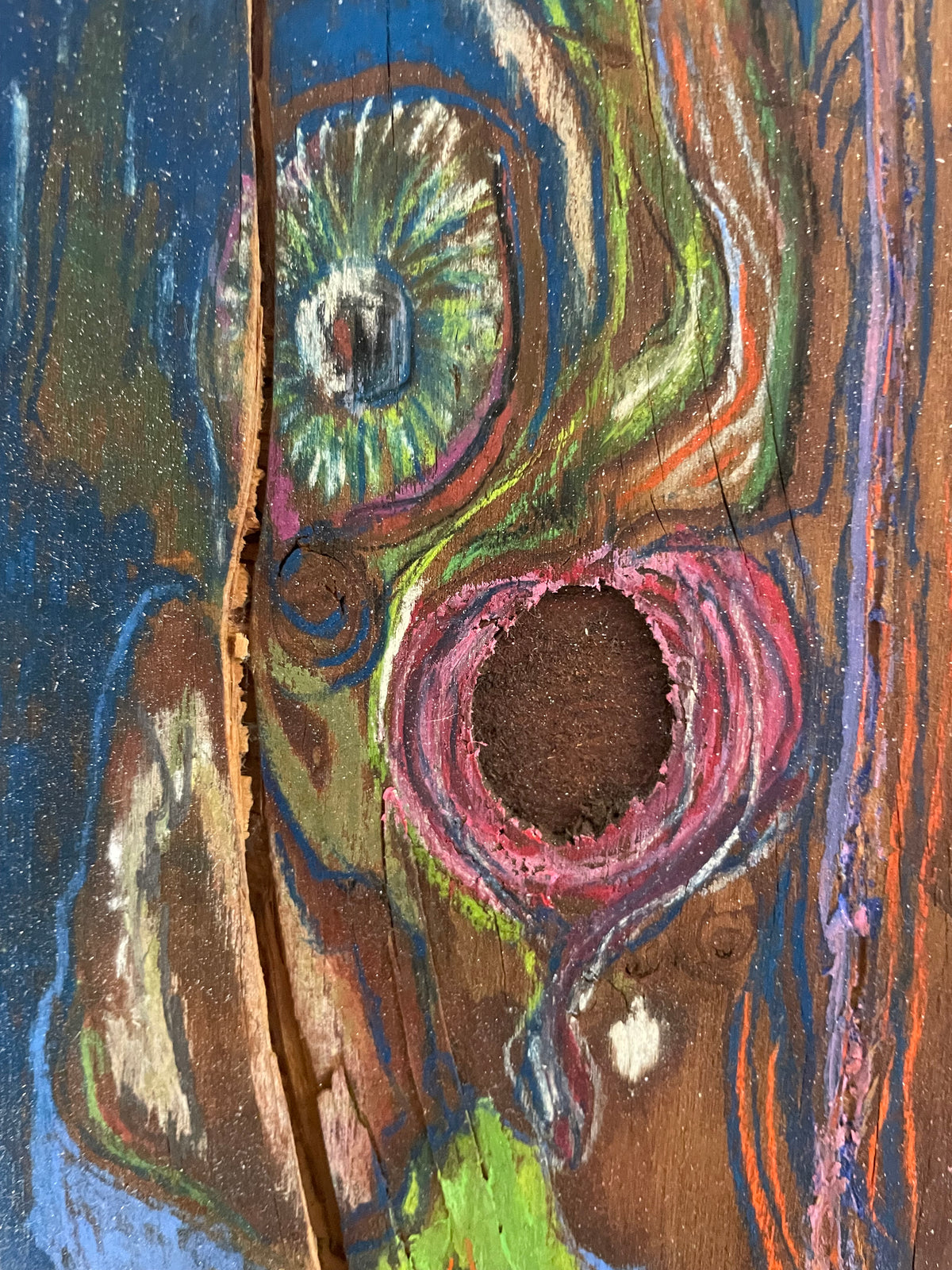 Colorful abstract painting of a face on a wooden surface