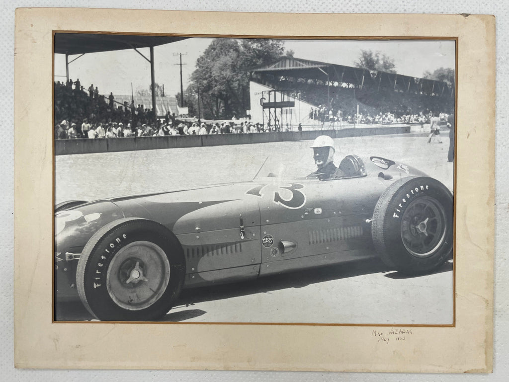 Vintage black and white photograph of auto racing driver ;Mike Nazaruk (aka Iron Mike) at the Indy 500 sitting in the cockpit pf his #73 Offenhauser Roadster, 1953.