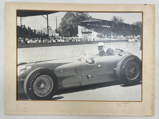 Vintage black and white photograph of auto racing driver ;Mike Nazaruk (aka Iron Mike) at the Indy 500 sitting in the cockpit pf his #73 Offenhauser Roadster, 1953.