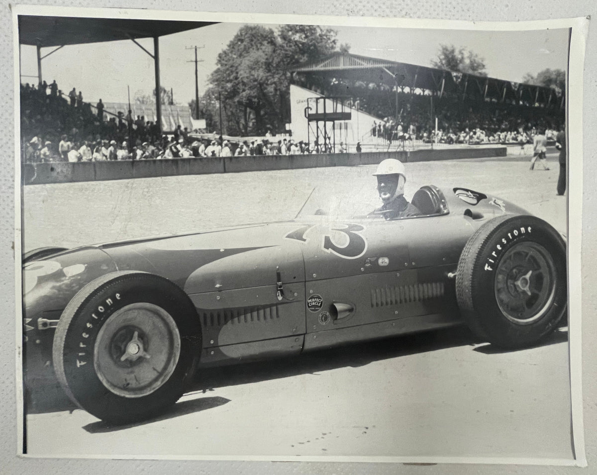 lack and white photograph of auto racing driver Mike Nazaruk (aka Iron Mike) at the Indy 500 sitting in the cockpit pf his #73 Offenhauser Roadster, 1953.