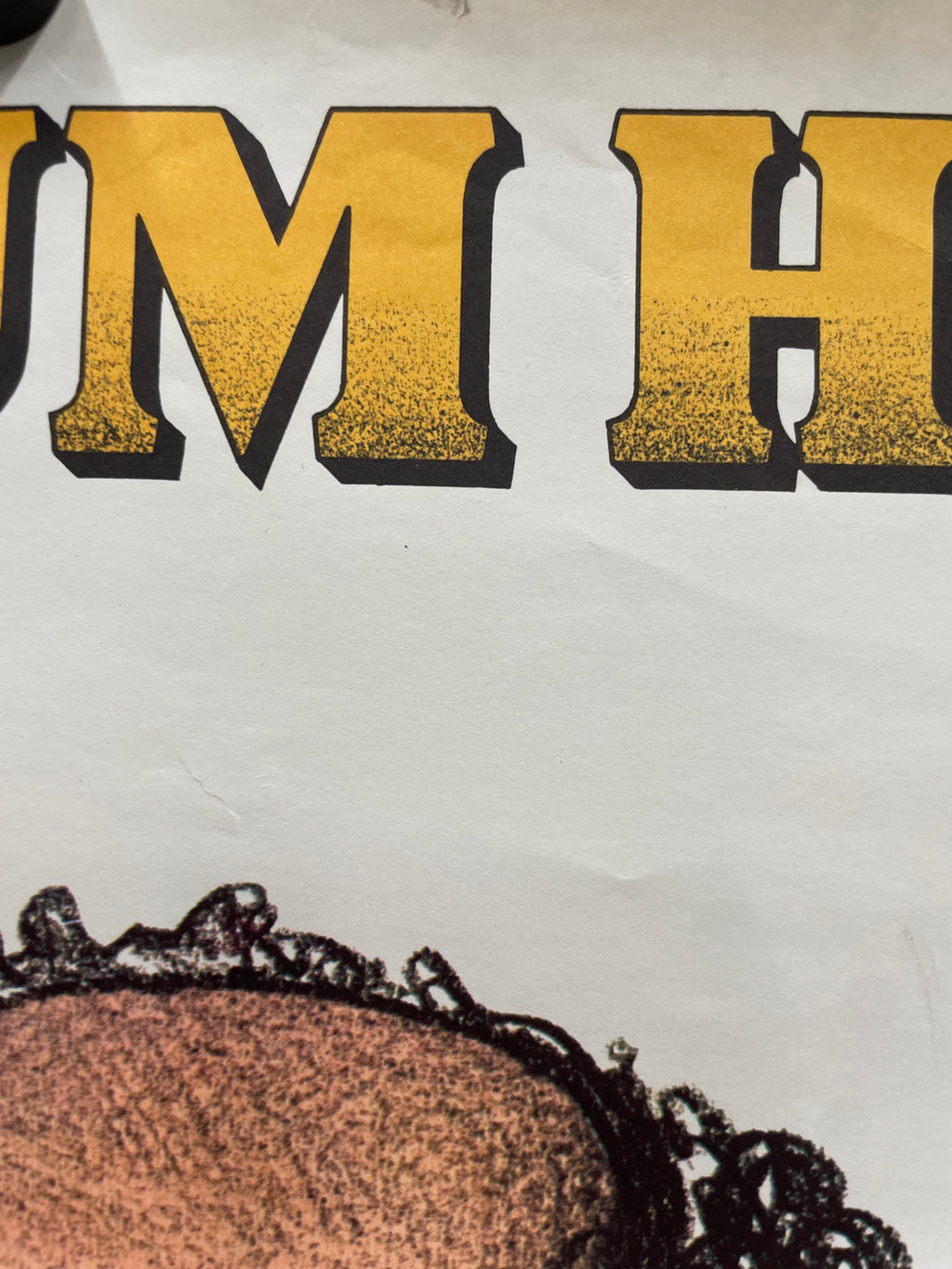 Close-up of a white shirt with yellow text and a brown circle design.