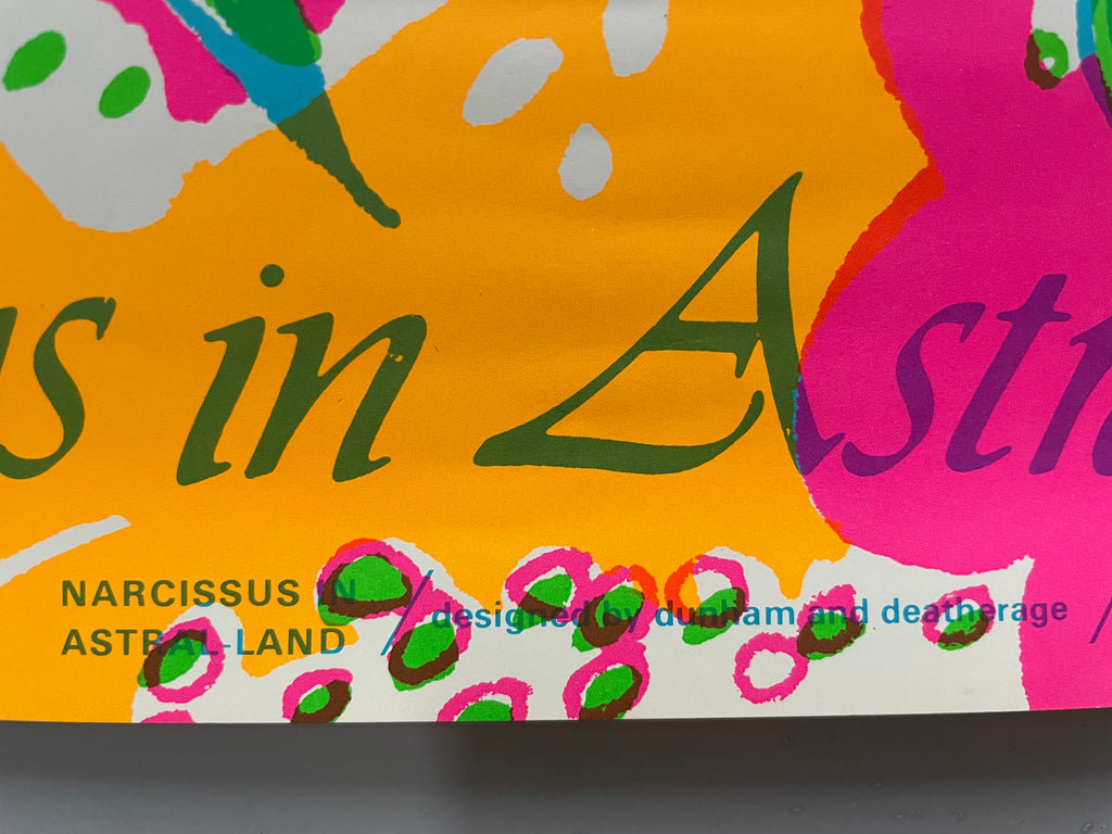 A close-up of a colorful book cover or printed artwork with abstract paint-like shapes in orange, pink, yellow, green, and white, plus dark green and purple lettering. Visible text includes 'Narcissus in Astral Land' and 'designed by dushram and deathrage'.