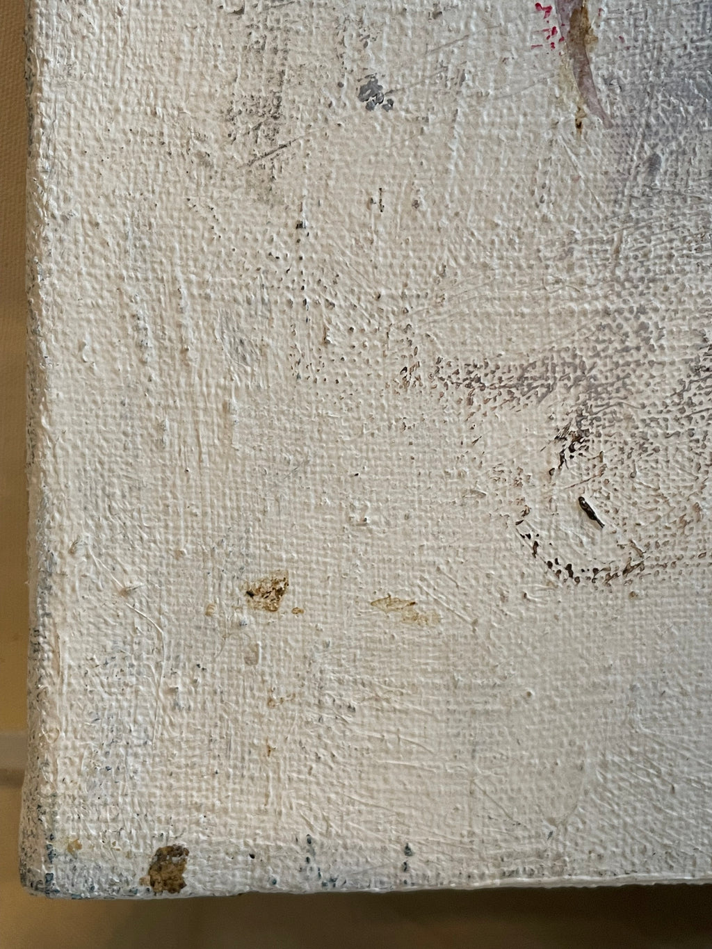 A close-up of a textured canvas or painted wood surface in an off-white, distressed finish with visible brushstrokes, scuffs, and small brown specks.