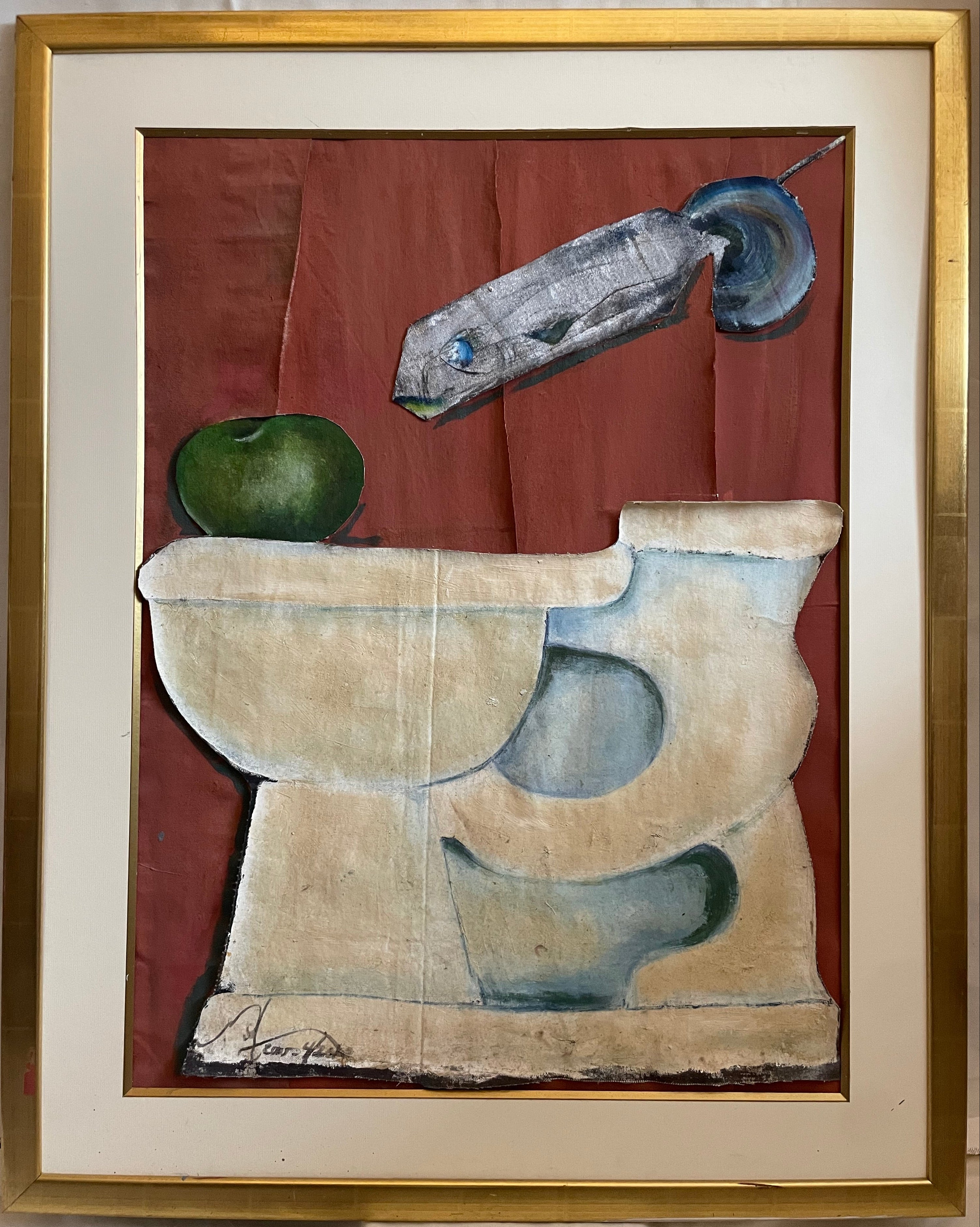 A framed abstract still life collage  featuring a red-brown background with a gray fish, a green apple, and cream-colored toilet, enclosed in a gold frame with an off-white mat.