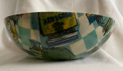 A hand-painted fabric and fiberglass bowl featuring a whimsical illustration of spices and condiments, a blue-and-white checkered pattern displayed against a draped white fabric background.