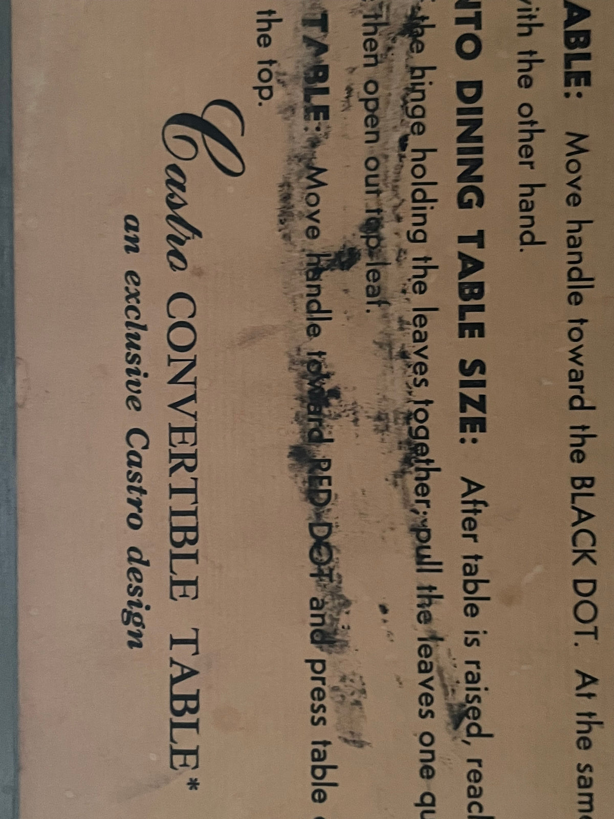 A close-up of a vintage printed instruction or care label for a convertible table, with black text on tan paper and visible wear and stains.