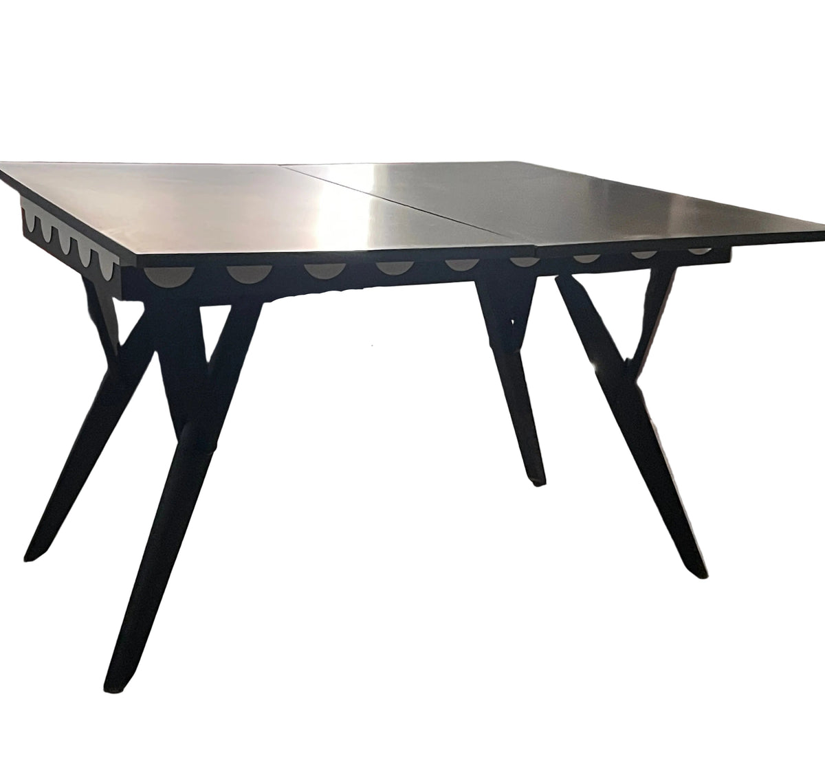 A black extendable dining table with angled legs and scalloped aprons.