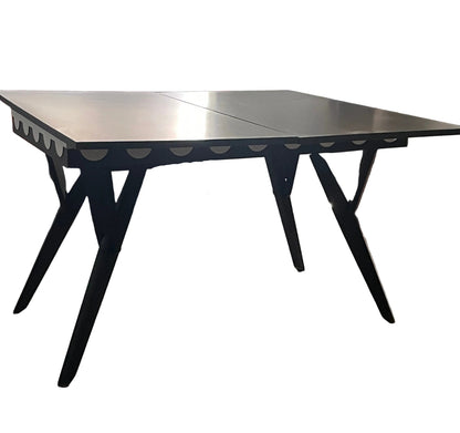 A black extendable dining table with angled legs and scalloped aprons.
