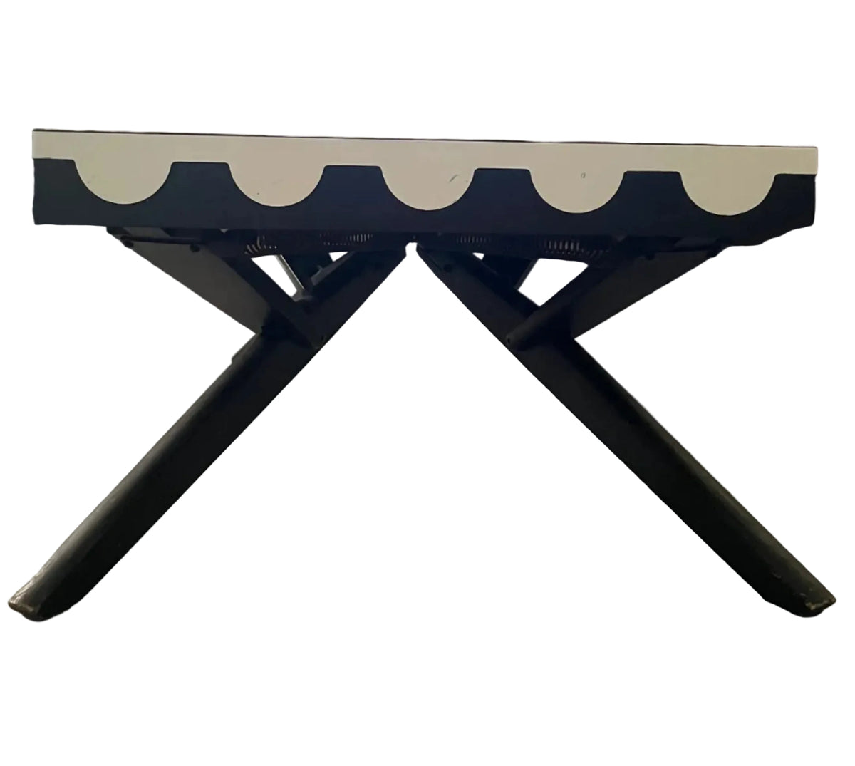 A mid-century modern lounge chair with a brown upholstered seat, a white scalloped front trim, and black metal X-style legs, set in a living room with wood floors and a bookshelf.
